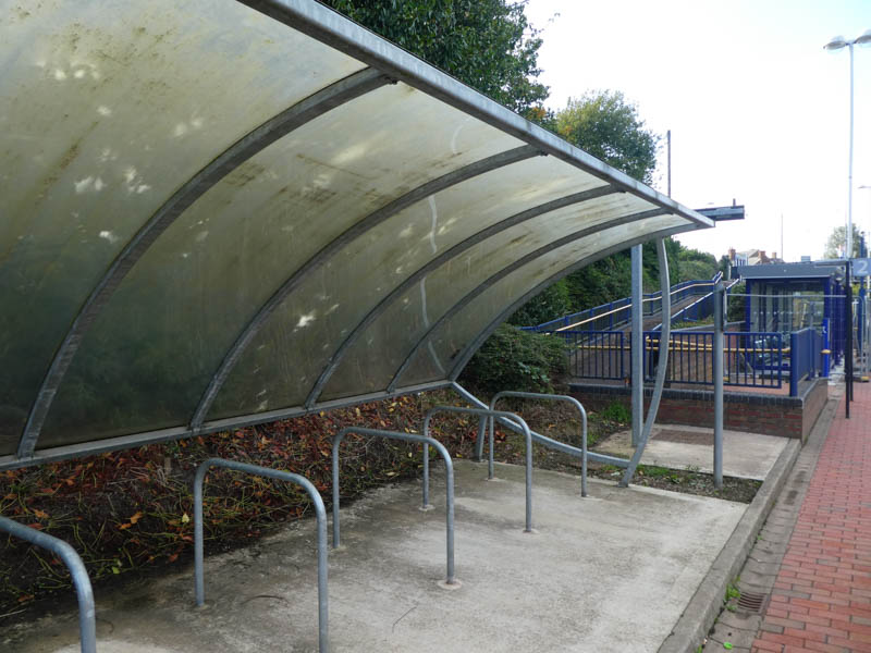 A mossy bike shelter, and behind it the (still barriered off when we visited) shiny new human shelter