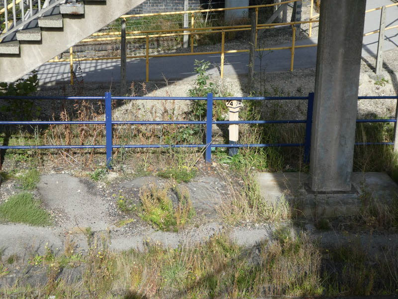 A milepost hidden underneath the footbridge