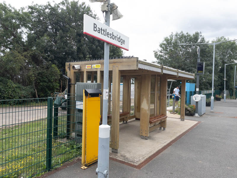 On the platform at Battlesbridge, with a wooden shelter and a few planters