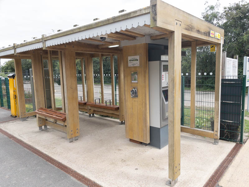 The shelter is of wood and incorporates a ticket machine.
