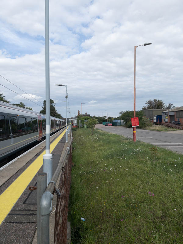 The platform has been extended to allow ten car trains, so the station building is only just visible in the distance, with the station's car parking on the right.