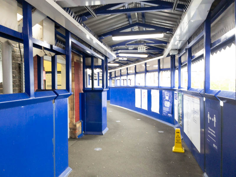 In the footbridge, with the station building on the left.